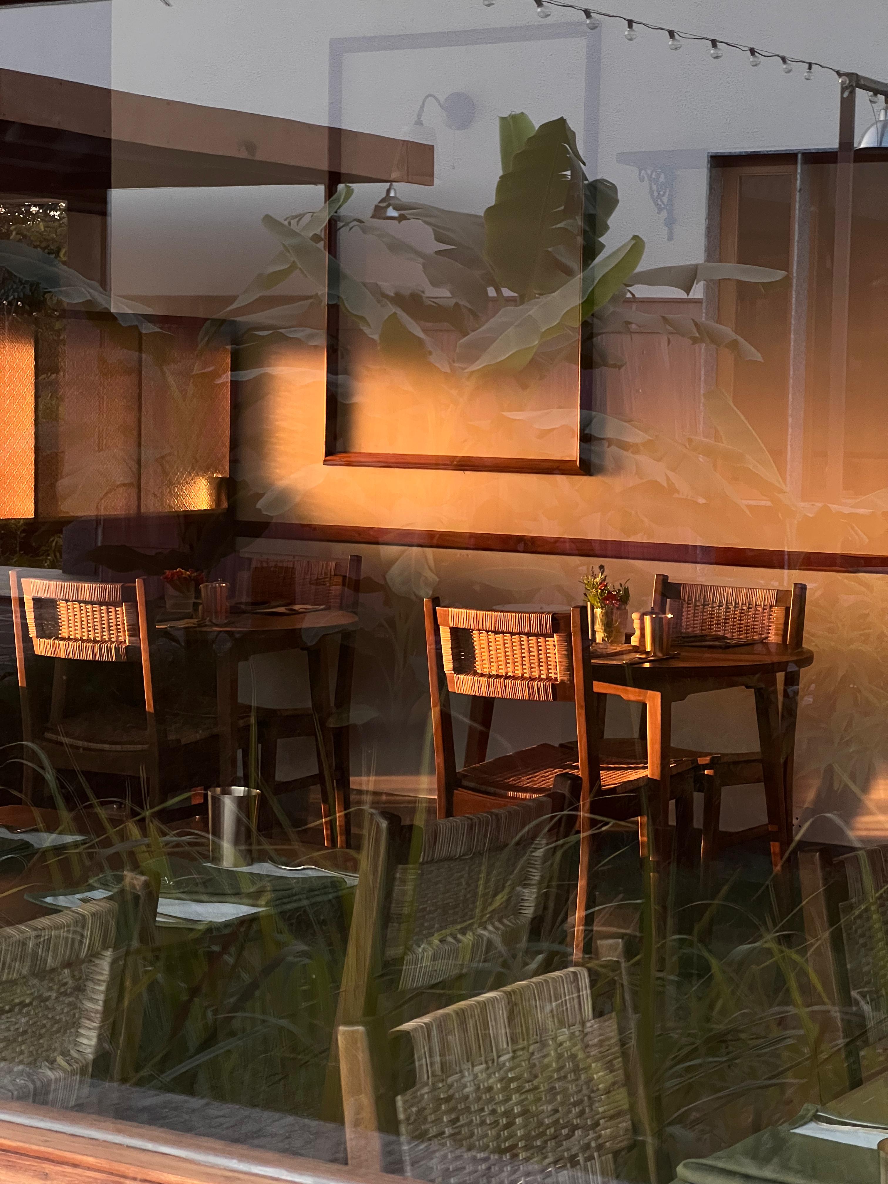 Dining tables reflecting the sunset through a window
